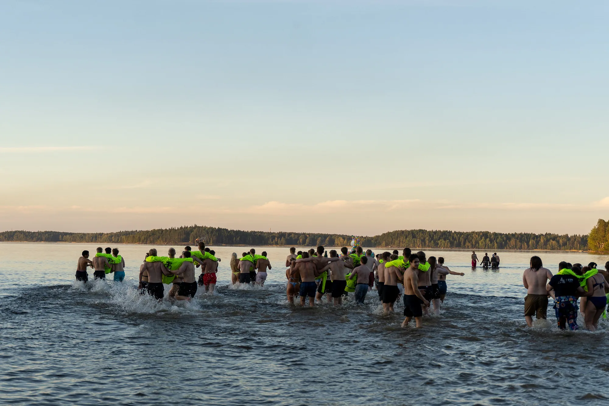 Opiskelijoita juoksemassa Saimaaseen auringonlaskussa Beach Partyssa